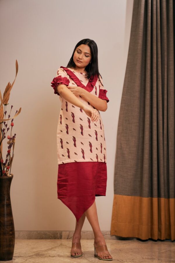 "Asymmetrical hemline dress with frilled sleeve panels. Comfortable loose fit with wooden button detailing."